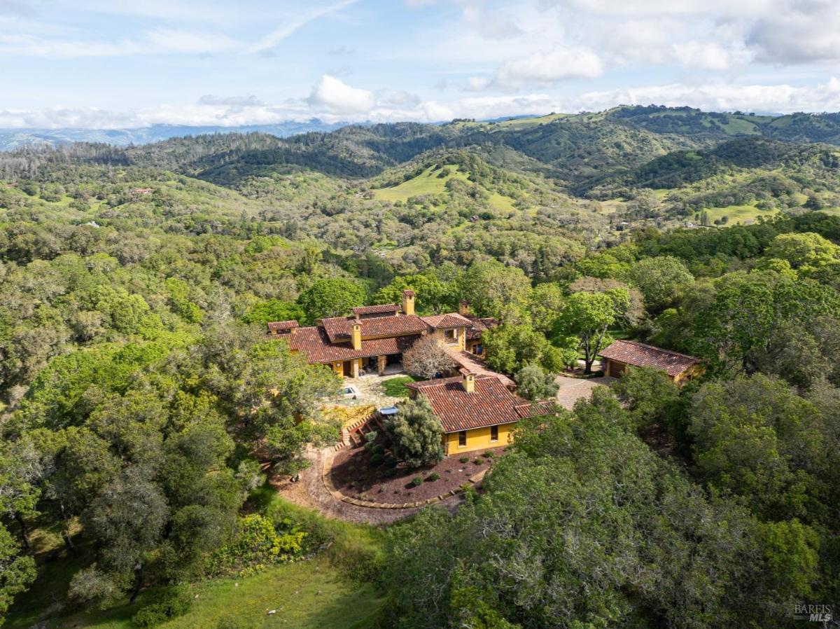 An aerial view of a home and surrounding green hills.