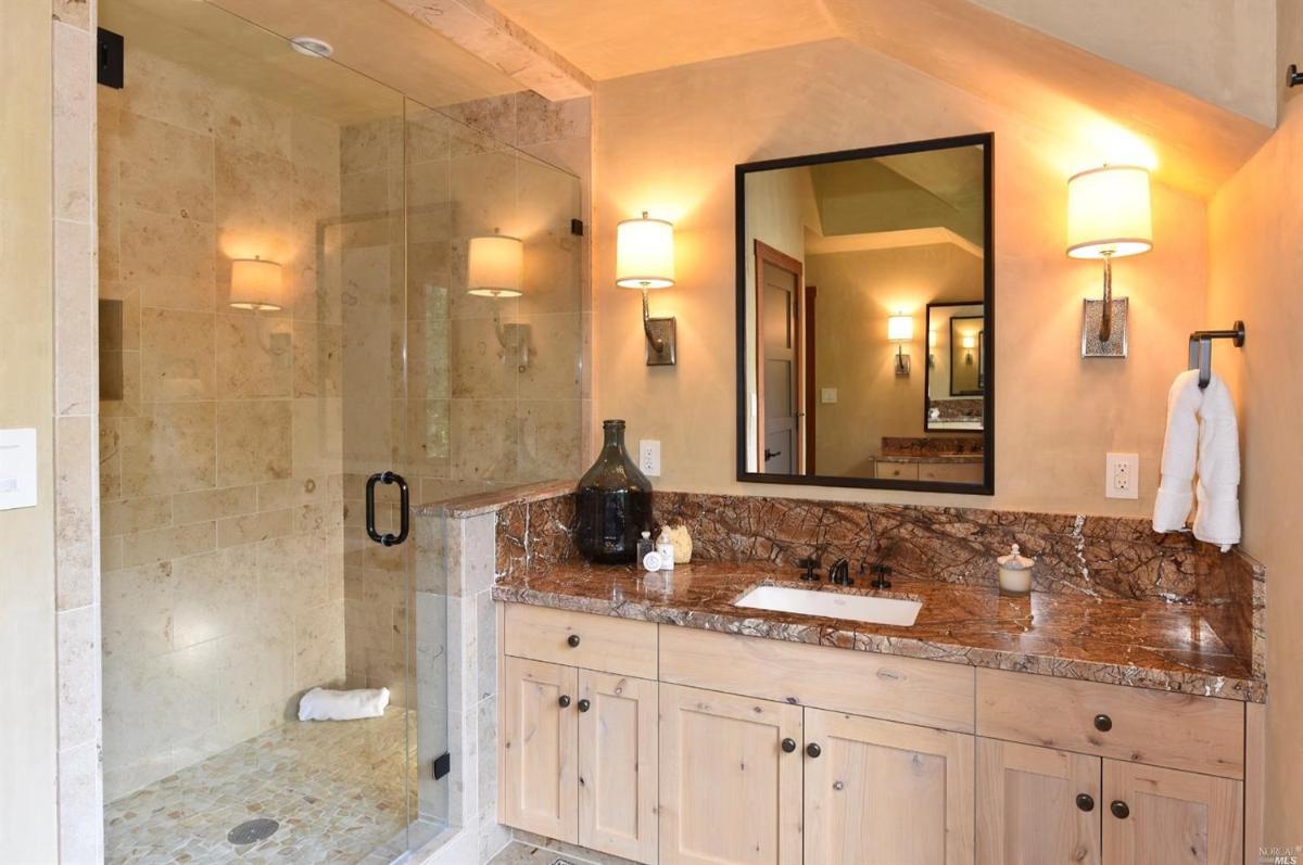 A bathroom with double sinks, wooden accents, and a glass-enclosed shower.