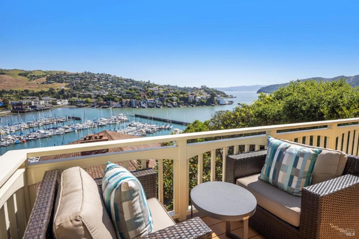 Balcony view of a marina, sailboats, and surrounding hills.