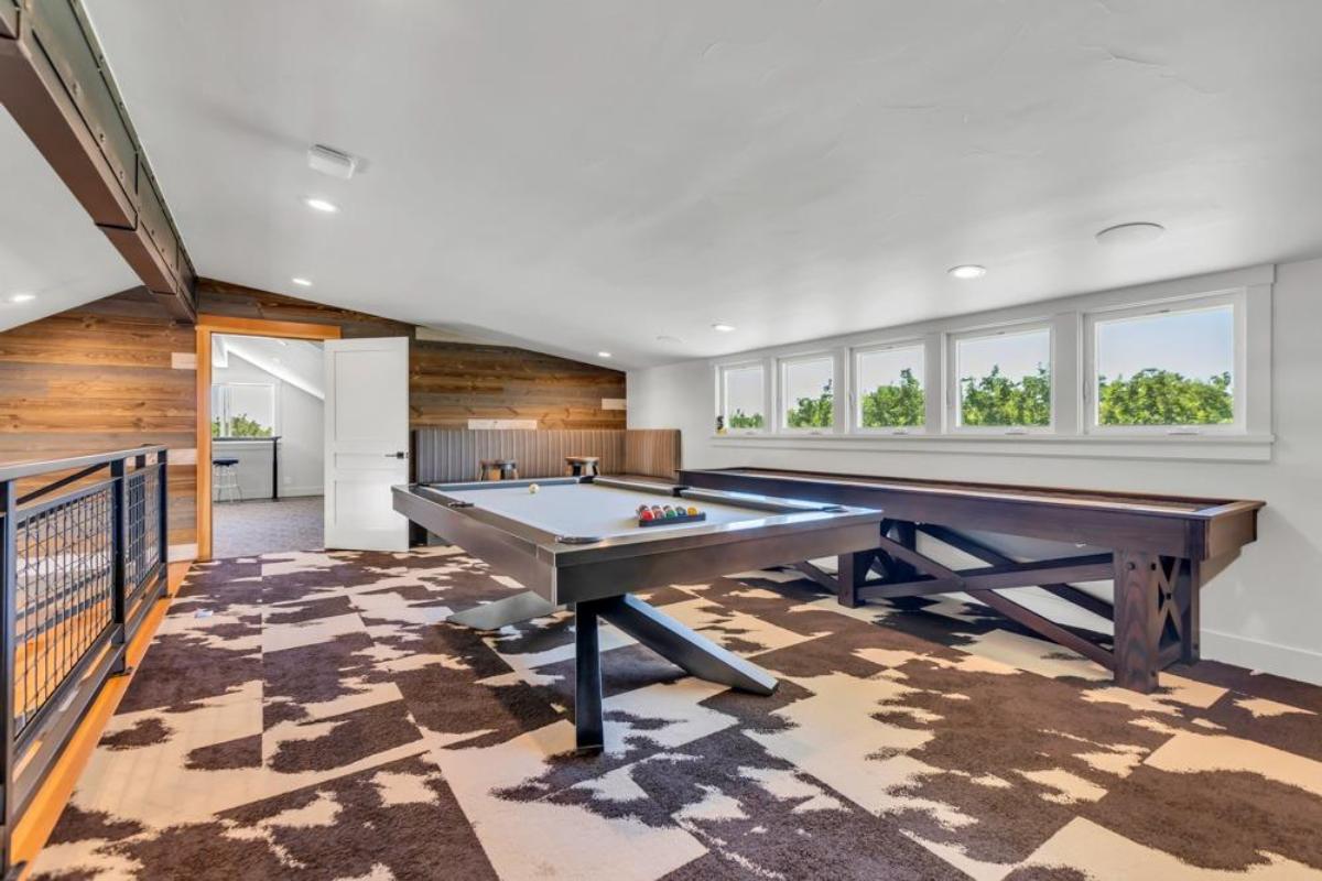 A game area features a pool table and seating along with windows for natural light.