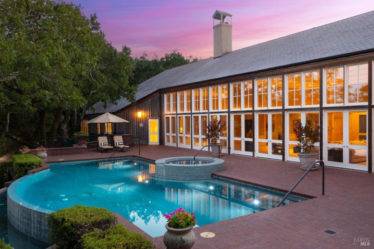 Pool and patio area at dusk with large glass windows reflecting light.