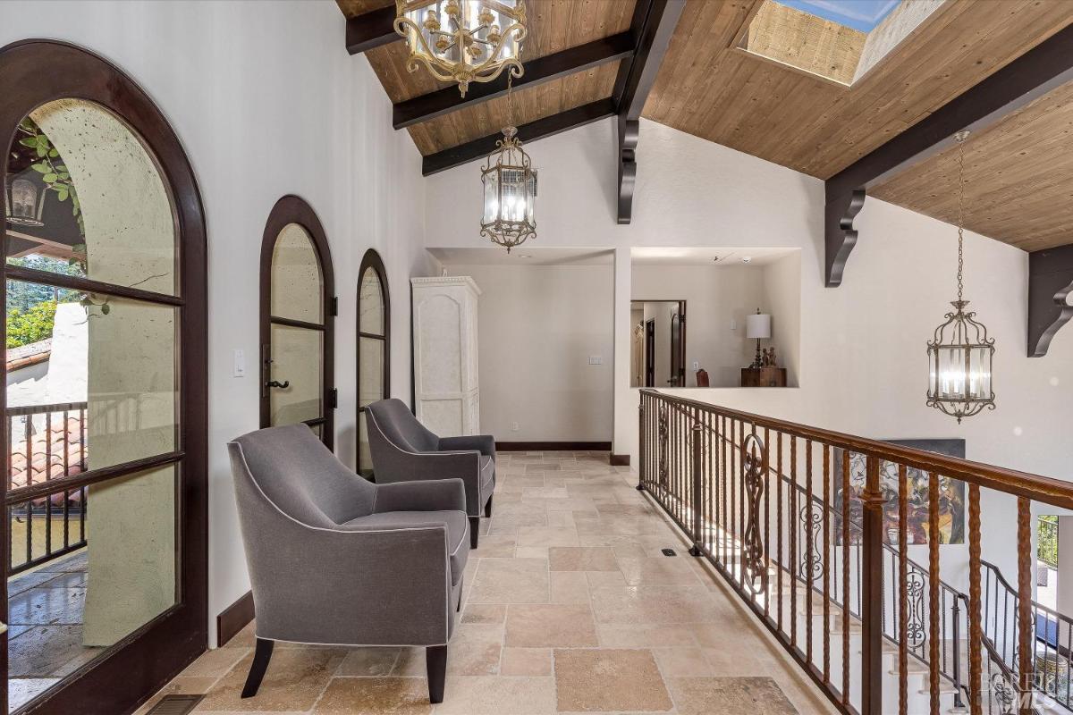 A loft with seating, arched windows, and railings.