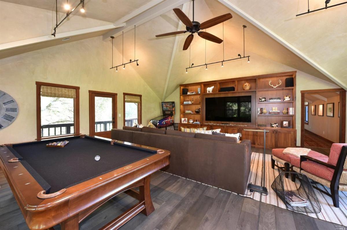 A game room with a pool table, built-in shelves, and a seating area.