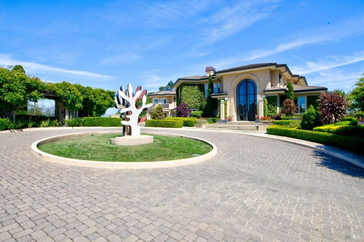 Circular driveway with a sculpture in the center and the main house in the background.