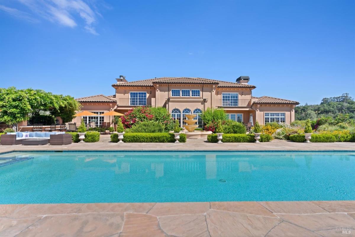 Mediterranean-style home sits beyond a sparkling blue pool.