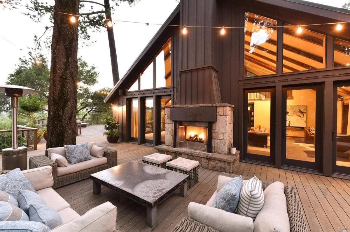 Outdoor patio with a fireplace, seating, and string lights.