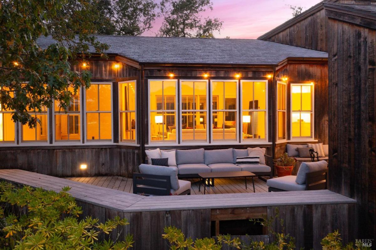 Outdoor seating area on a wooden deck with illuminated windows.