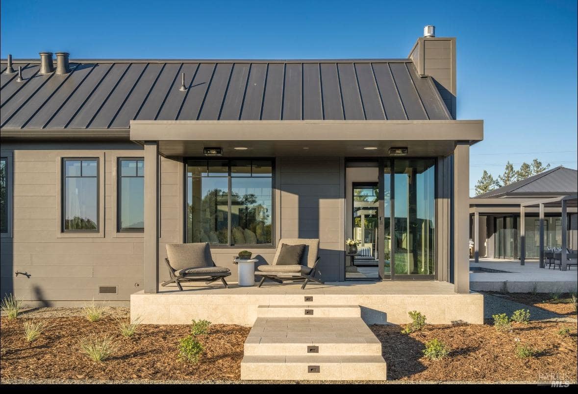 A patio area with two chairs, a small table, and sliding glass doors leading inside the home.