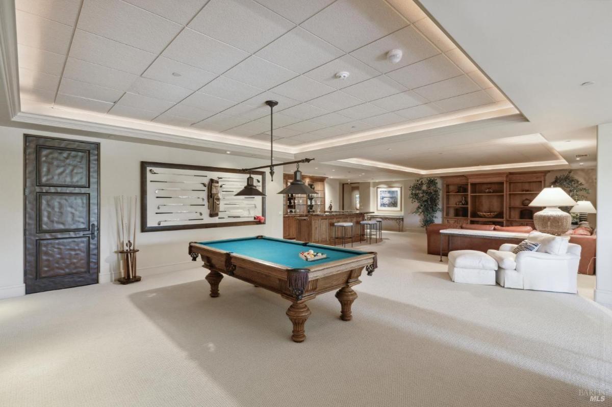 A game room featuring a pool table, casual seating, and a bar area. 