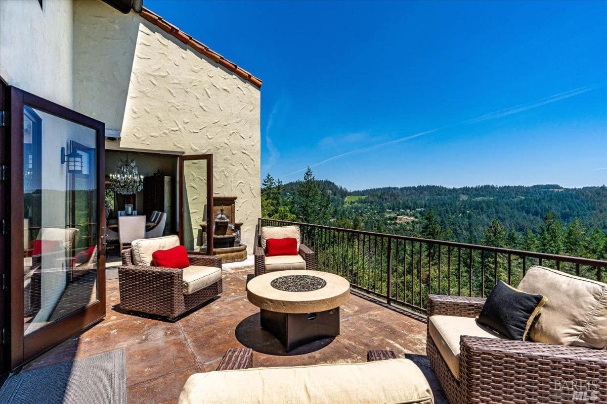 An outdoor terrace with wicker seating, a fire pit, and mountain views.