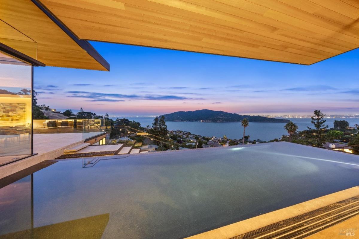 An infinity pool overlooking a bay and distant city lights.