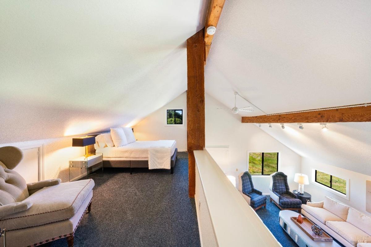 Loft bedroom with a sitting area overlooking the space below.