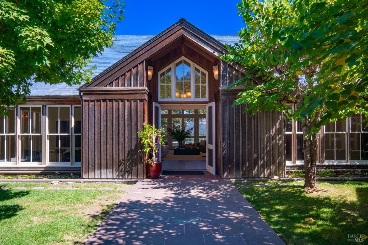 Front entrance of a wooden house with a gabled roof and glass panels.