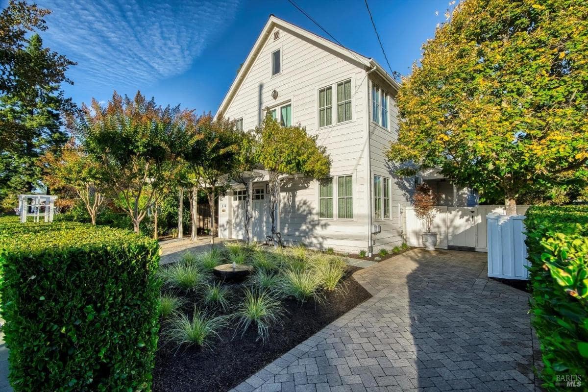 Front view of a white two-story house with a paved driveway and landscaped yard.