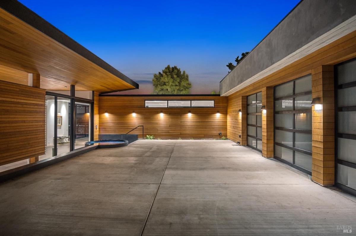 A courtyard with wood siding and glass garage doors.