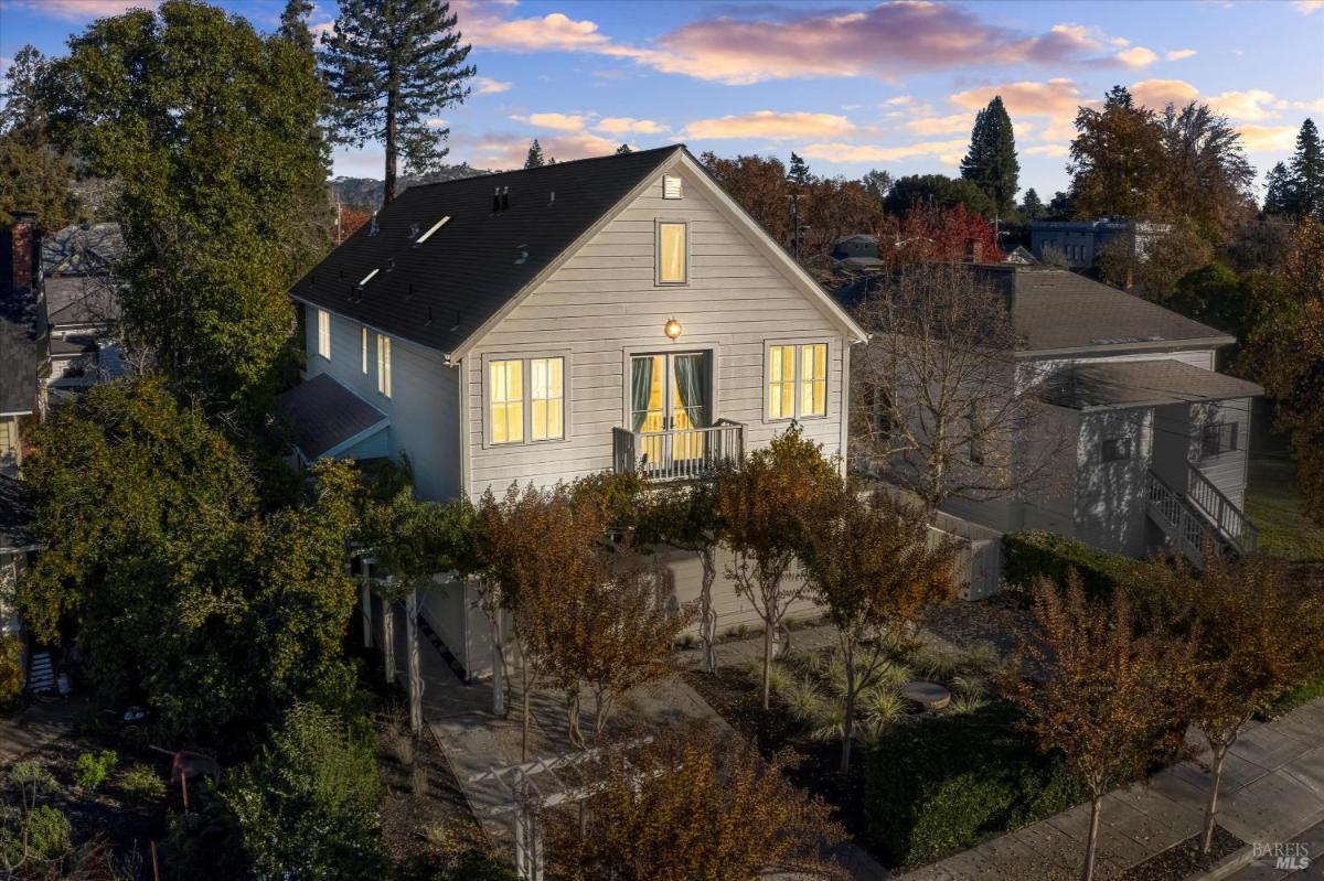 Evening view of a two-story house with trees and a balcony.