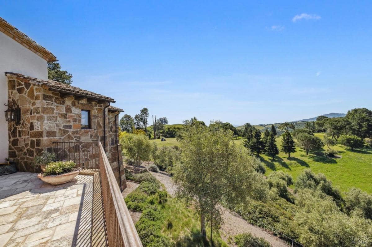 A stone balcony overlooking a green landscape with trees and a winding path.