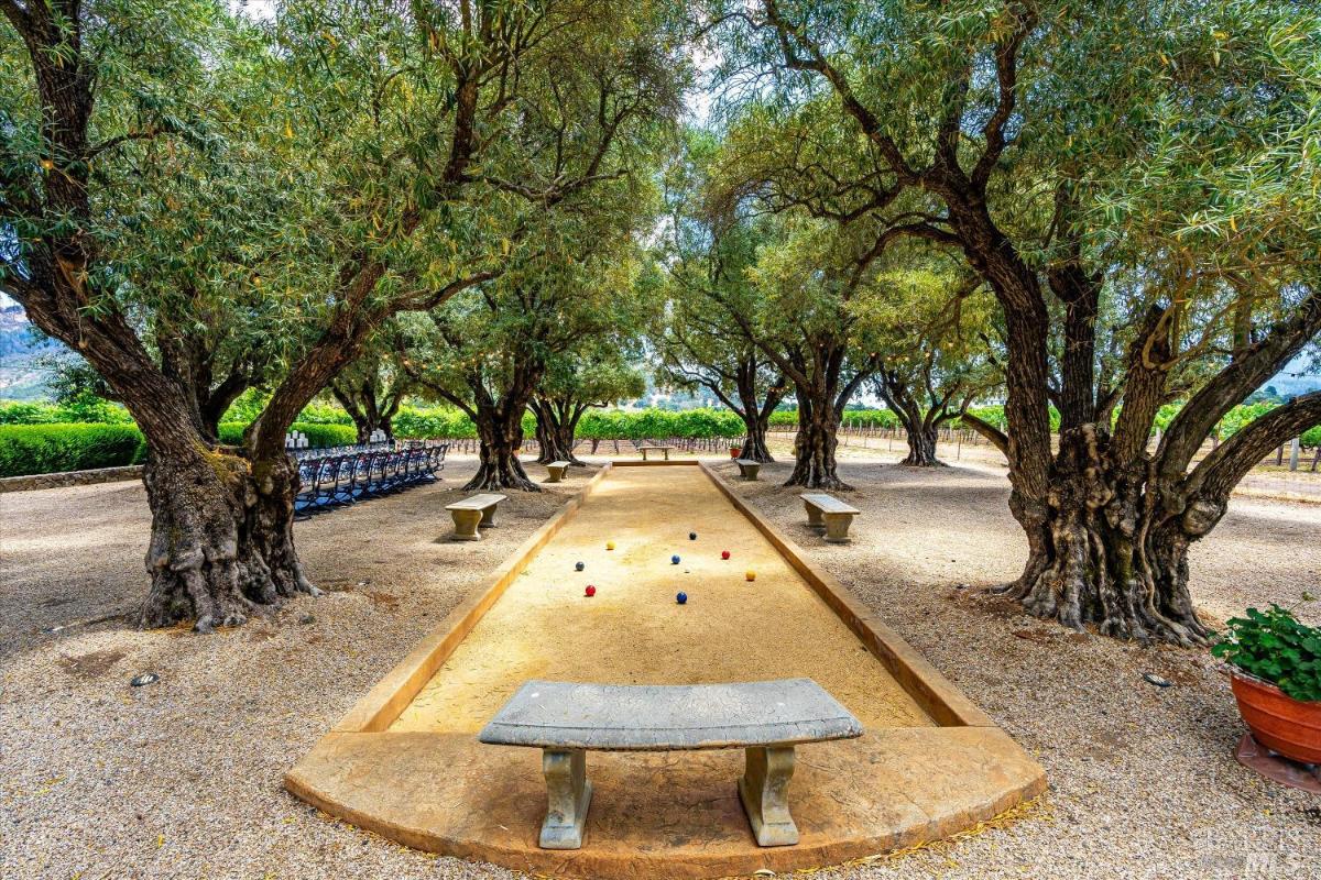 A bocce court right beside the outdoor dining area under the big trees.