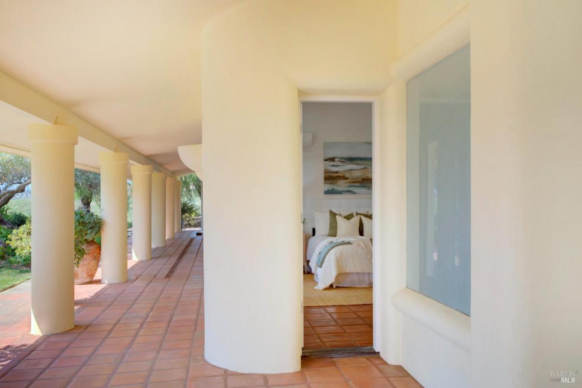 A hallway outside a bedroom with columns and terracotta tiles.