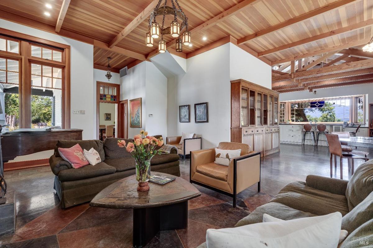 Open living space with seating, a kitchen, and visible wood beam ceiling.