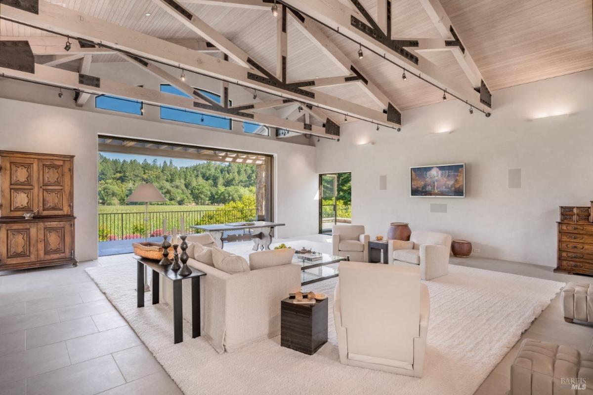 A living room with a view of the outdoors, featuring a seating area, a coffee table, and a large open doorway.