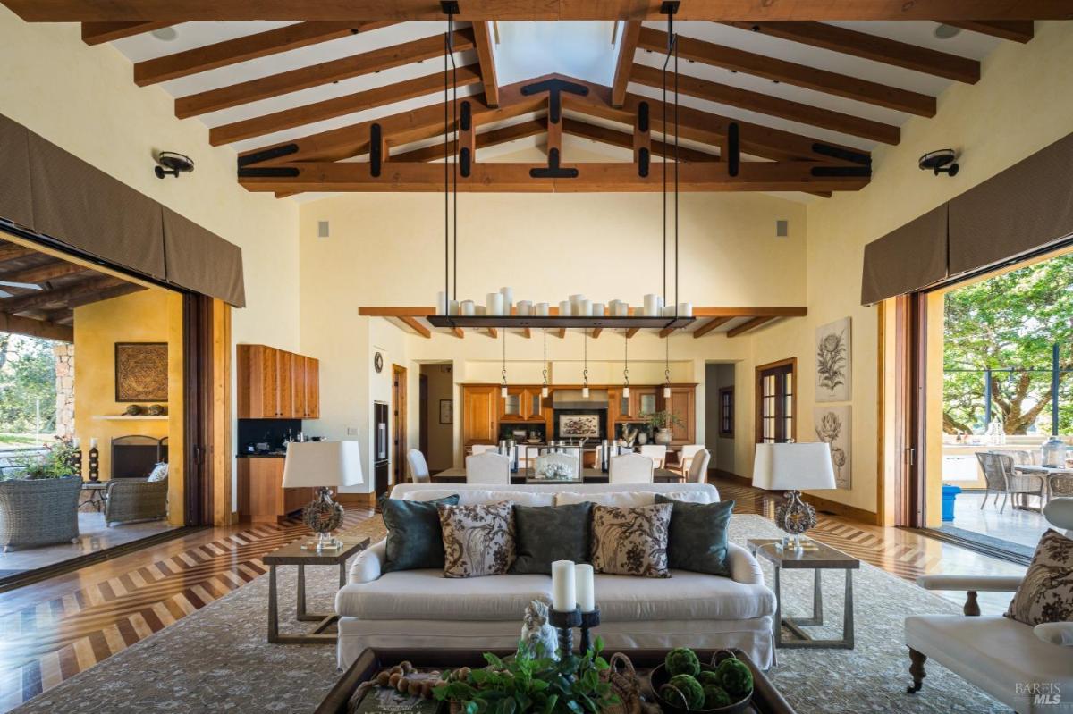 Open-plan living and dining area with a vaulted ceiling and wood beams.