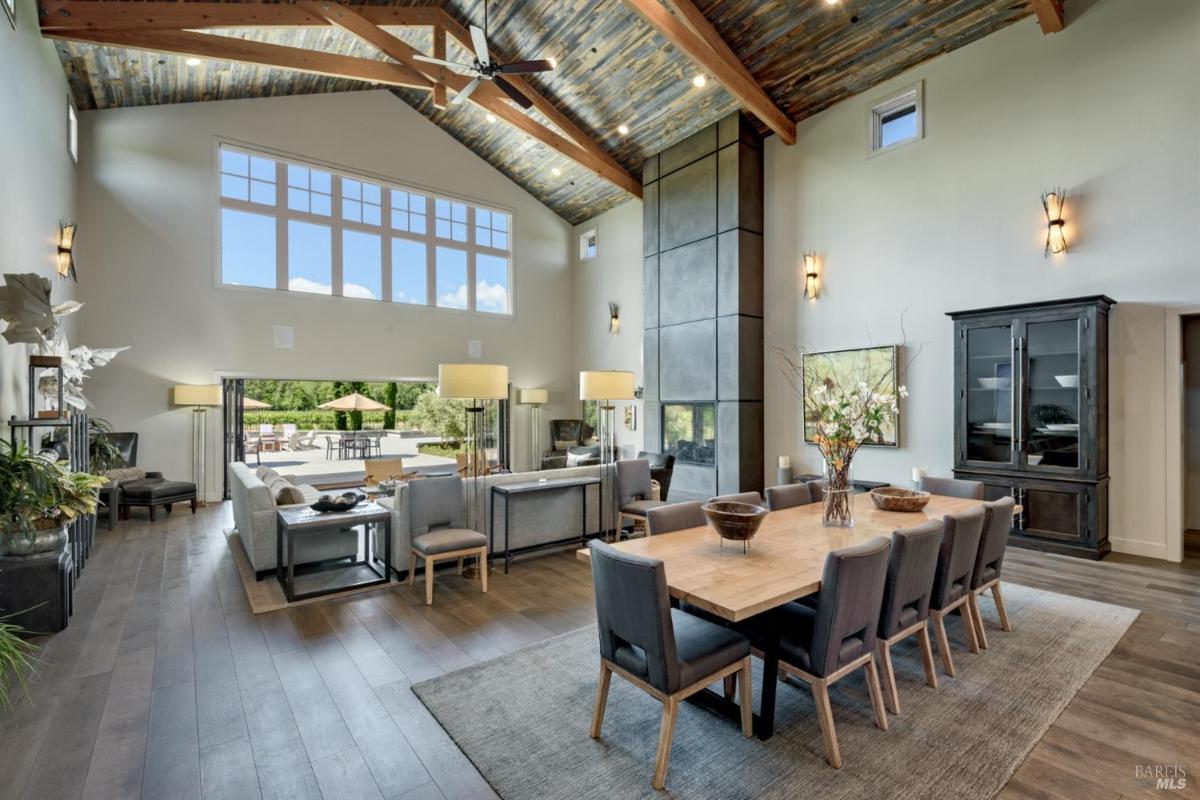 Open-plan living and dining area with large windows and exposed wooden beams.