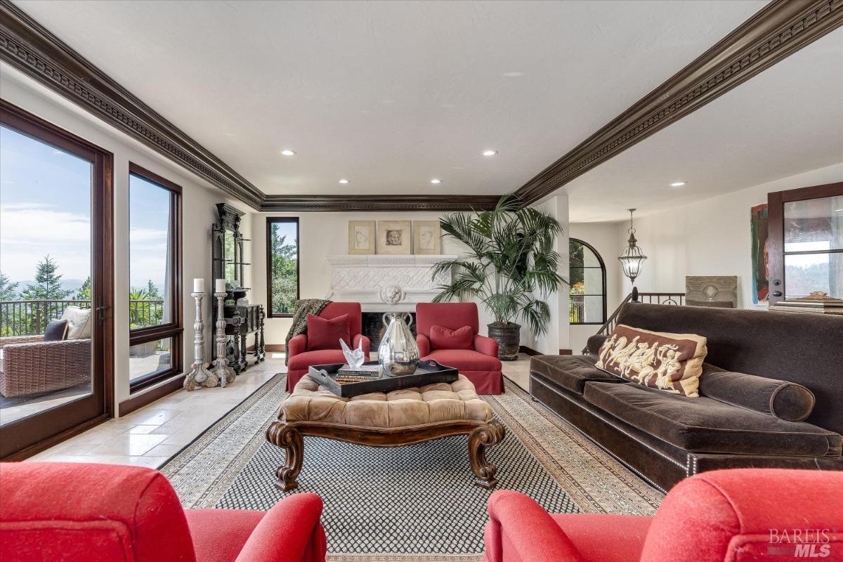 Living room with red chairs, brown sofa, and glass doors leading to a balcony.