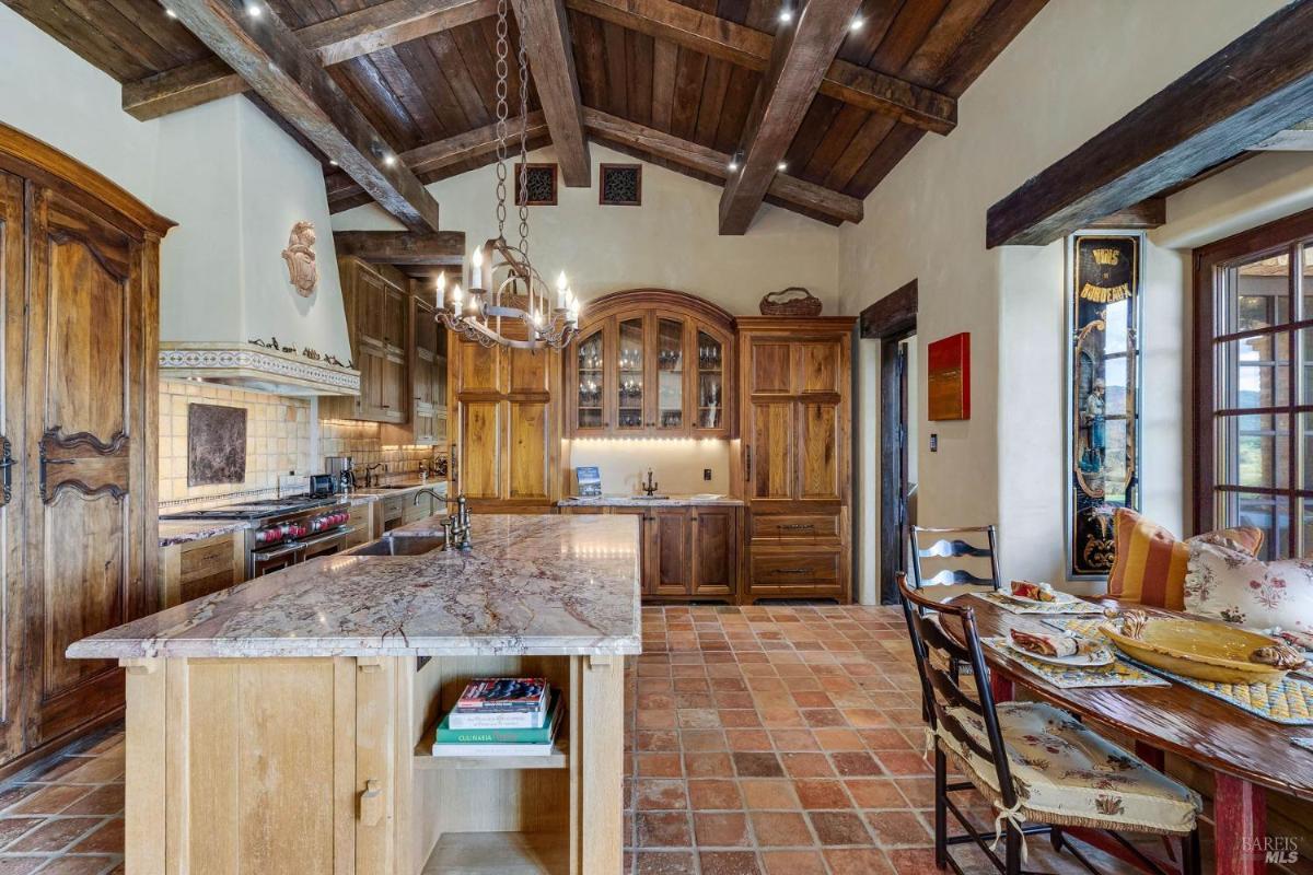 Kitchen with a marble island, wooden cabinets, and a chandelier.