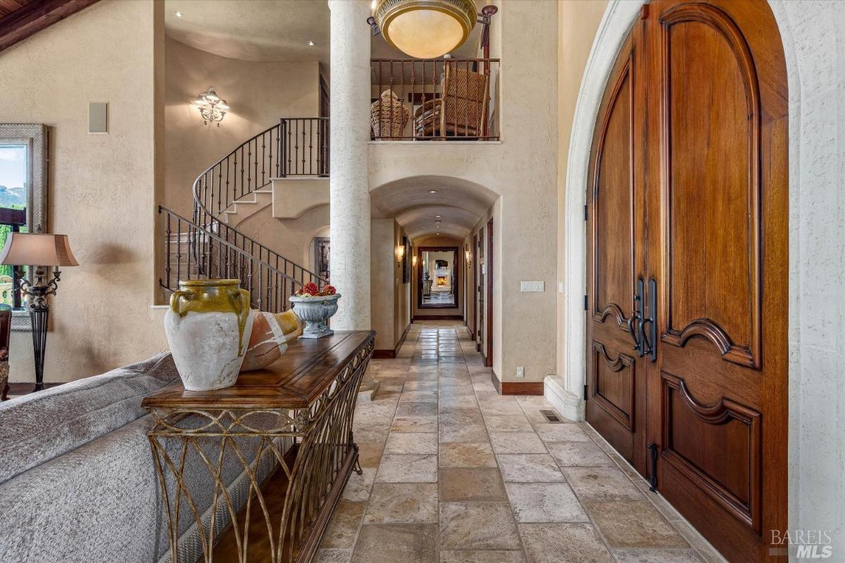 Foyer with tile flooring, a staircase, and a hallway leading to another room.