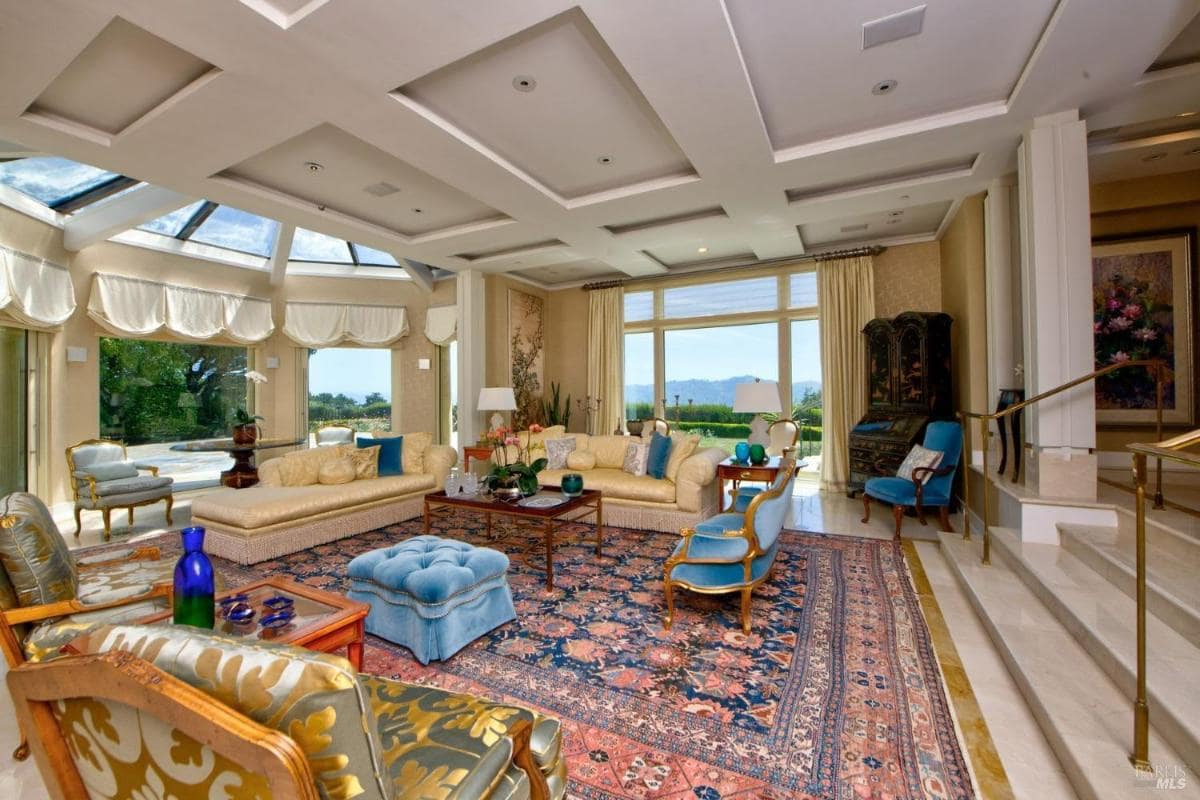 Living room with coffered ceilings, a glass dome skylight, and large windows offering views of the garden. 