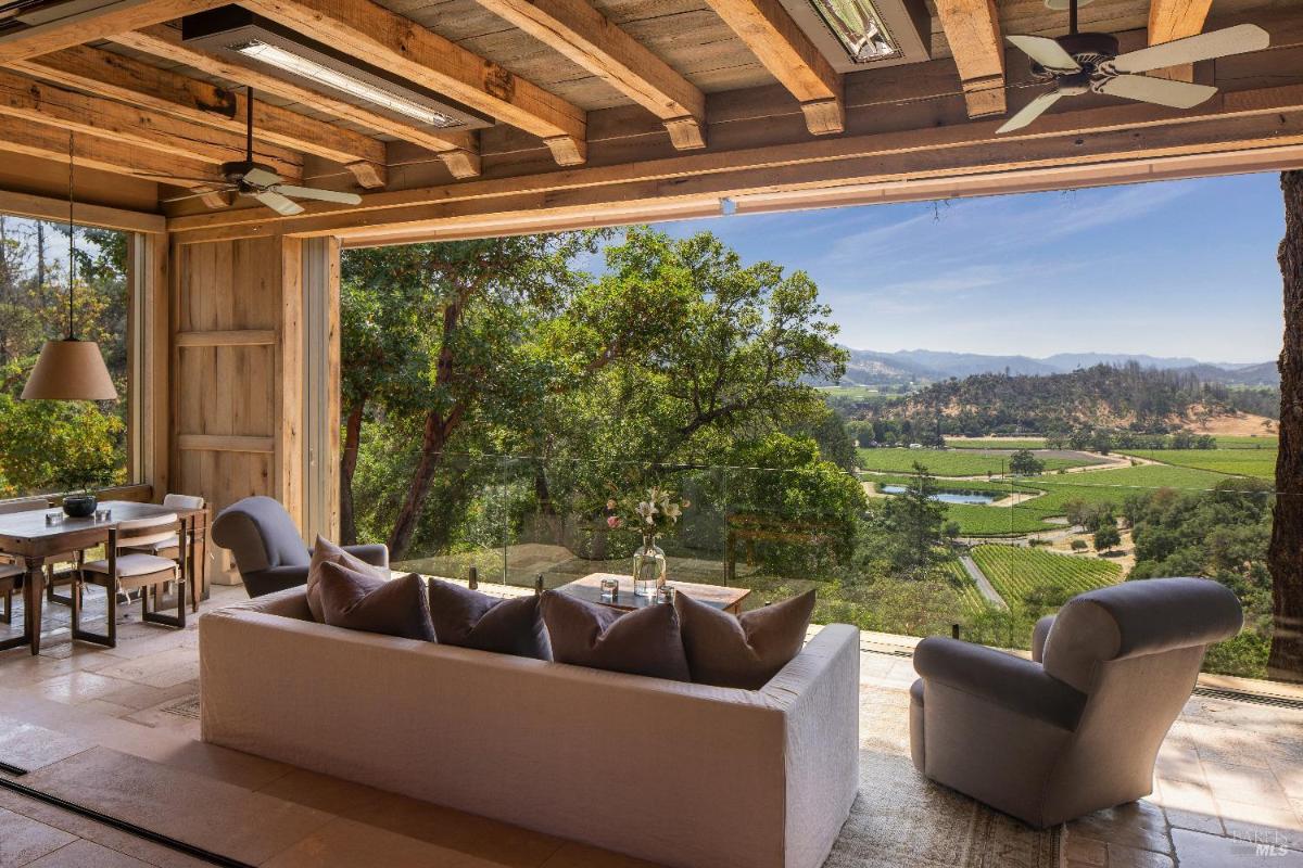 Indoor lounge with open walls and a view of vineyards and hills.