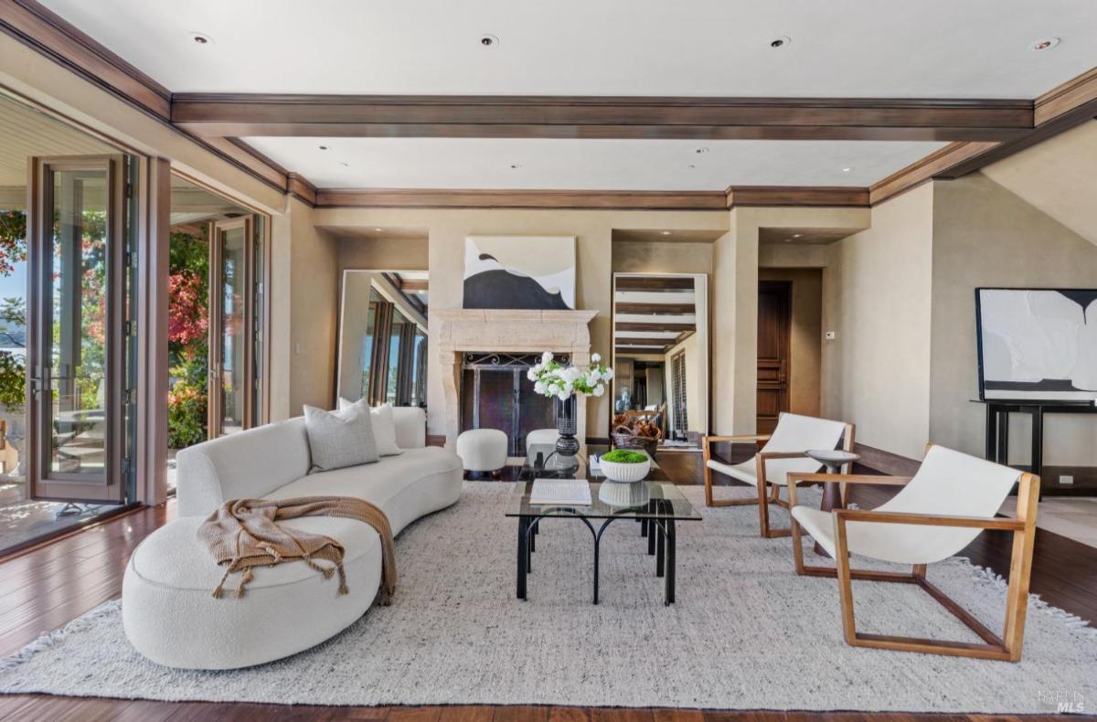 Living room featuring a curved sofa, coffee table, two chairs, a fireplace, and large windows.