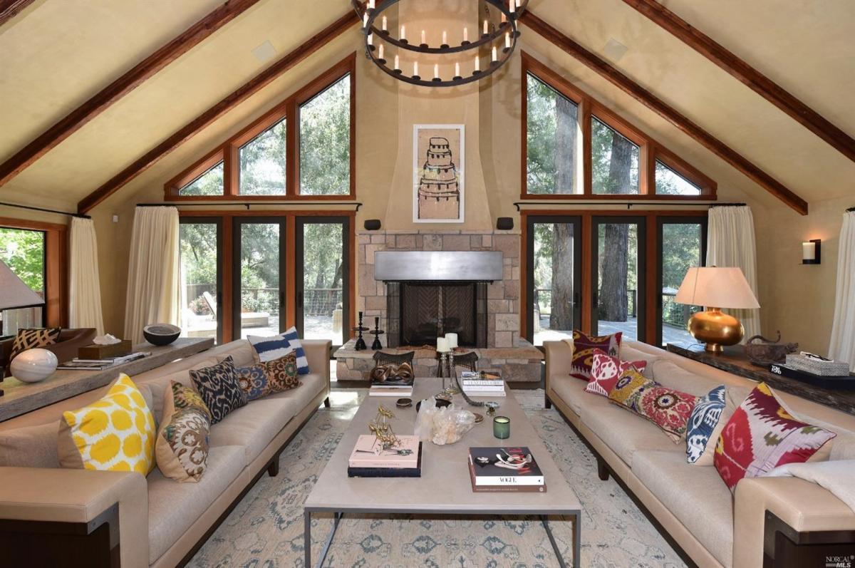 A living room with sofas, a stone fireplace, and tall triangular windows.