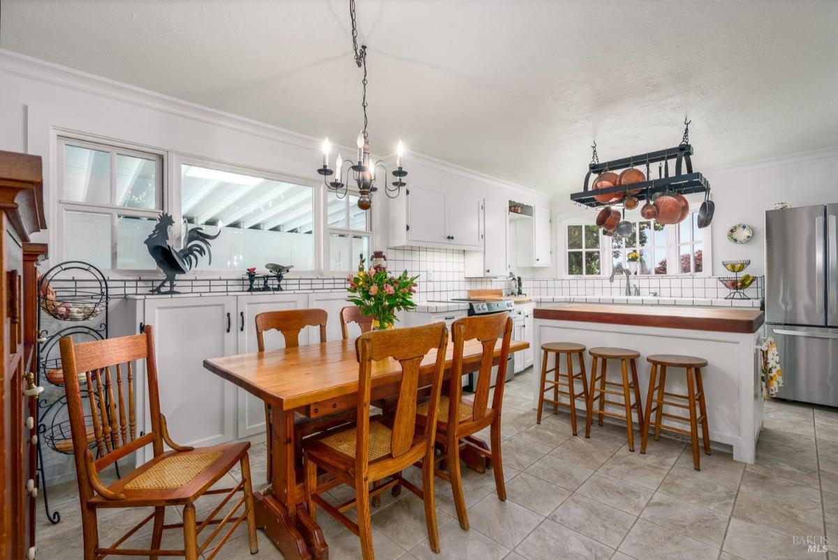 Kitchen with a dining table, white cabinets, and tiled backsplash.