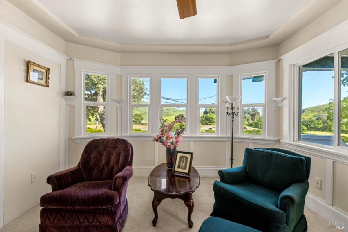 Seating area with large windows and green landscape views.