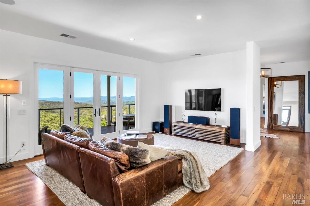 Living room featuring a leather sofa, a media console, and large windows with mountain views.