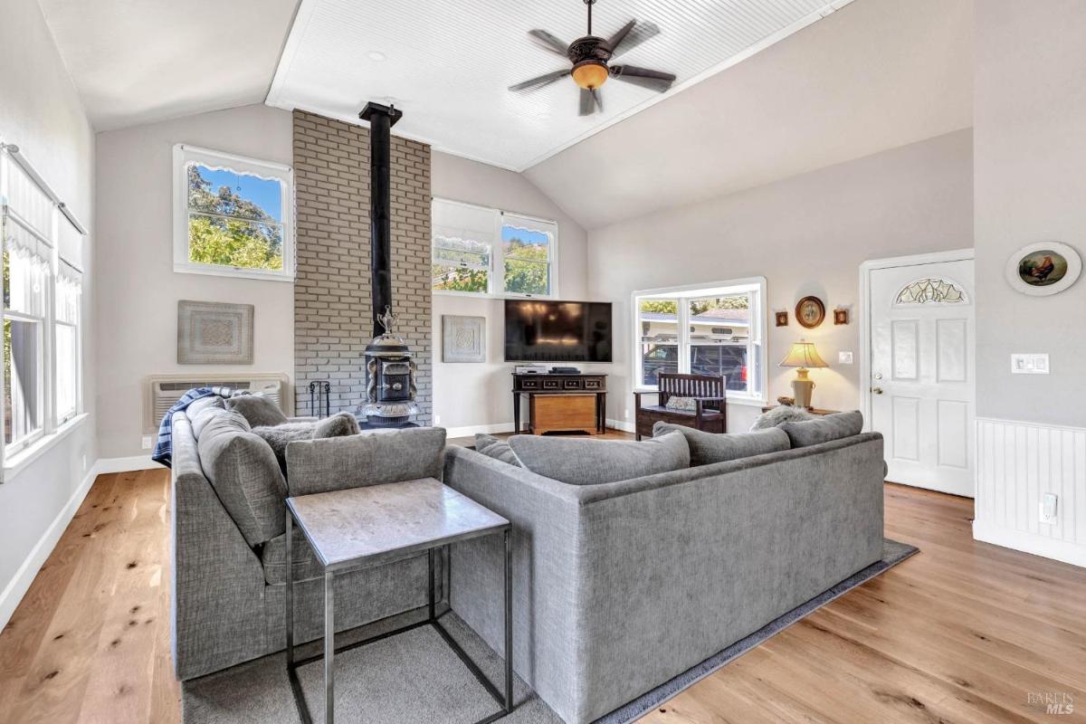 A family room featuring a wood-burning stove, a ceiling fan, and a sectional sofa.