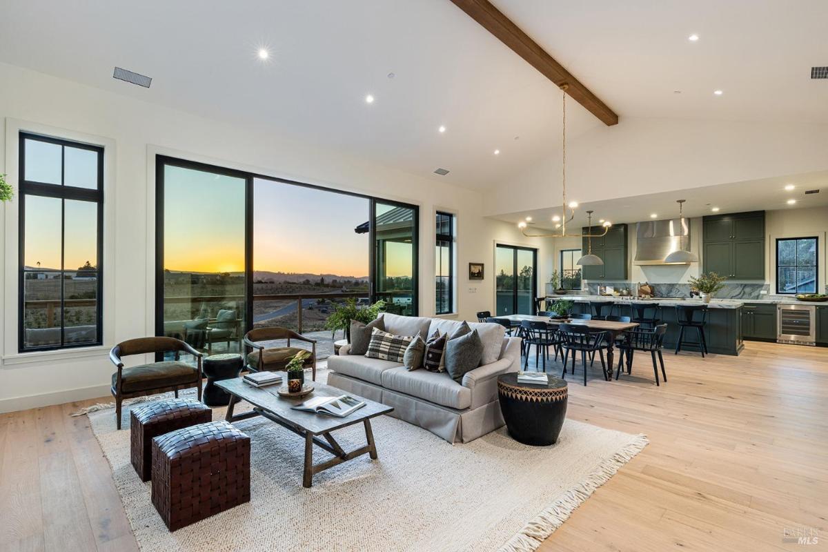 A spacious open-concept living area with large windows showcasing a sunset view.