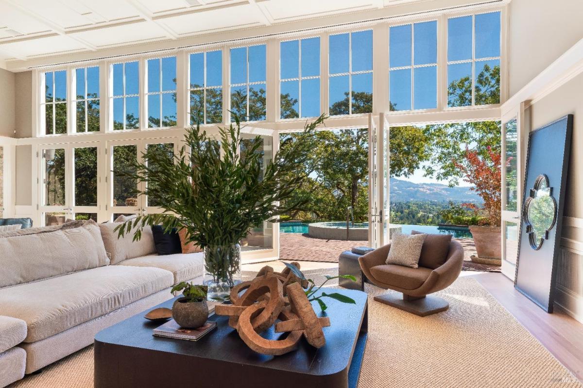 Living room with open glass doors leading to a pool and outdoor seating.