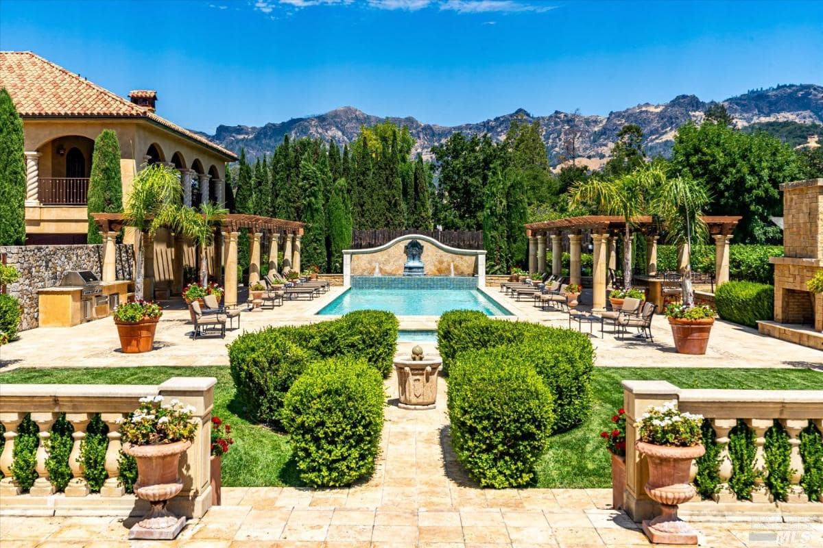 A view of a mansion with a vineyard in the background.