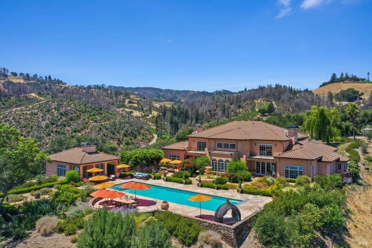 An aerial view reveals the sprawling mansion, outdoor pool, and lush landscaping surrounded by rolling hills. 