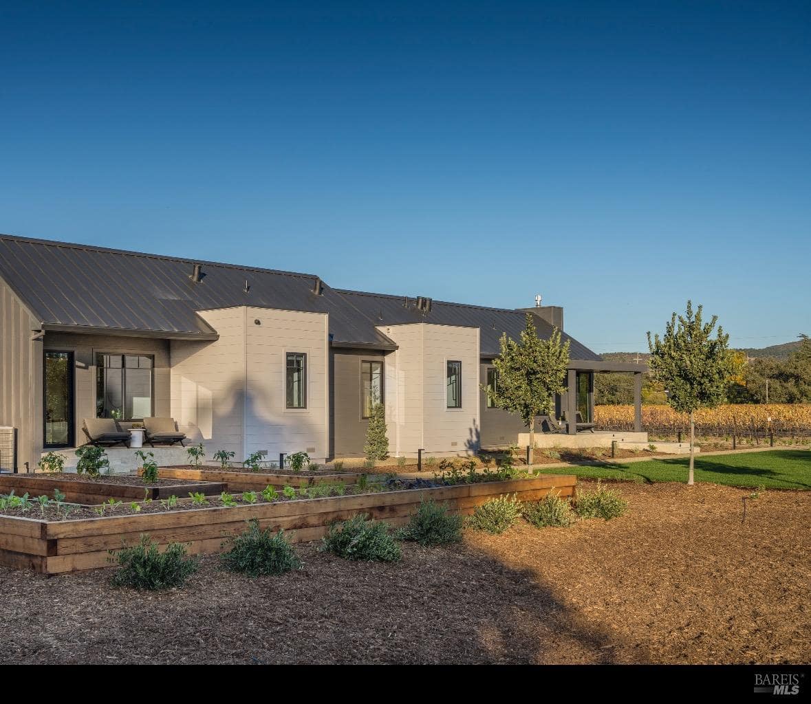 A modern home with raised garden beds and vineyard views in the background.