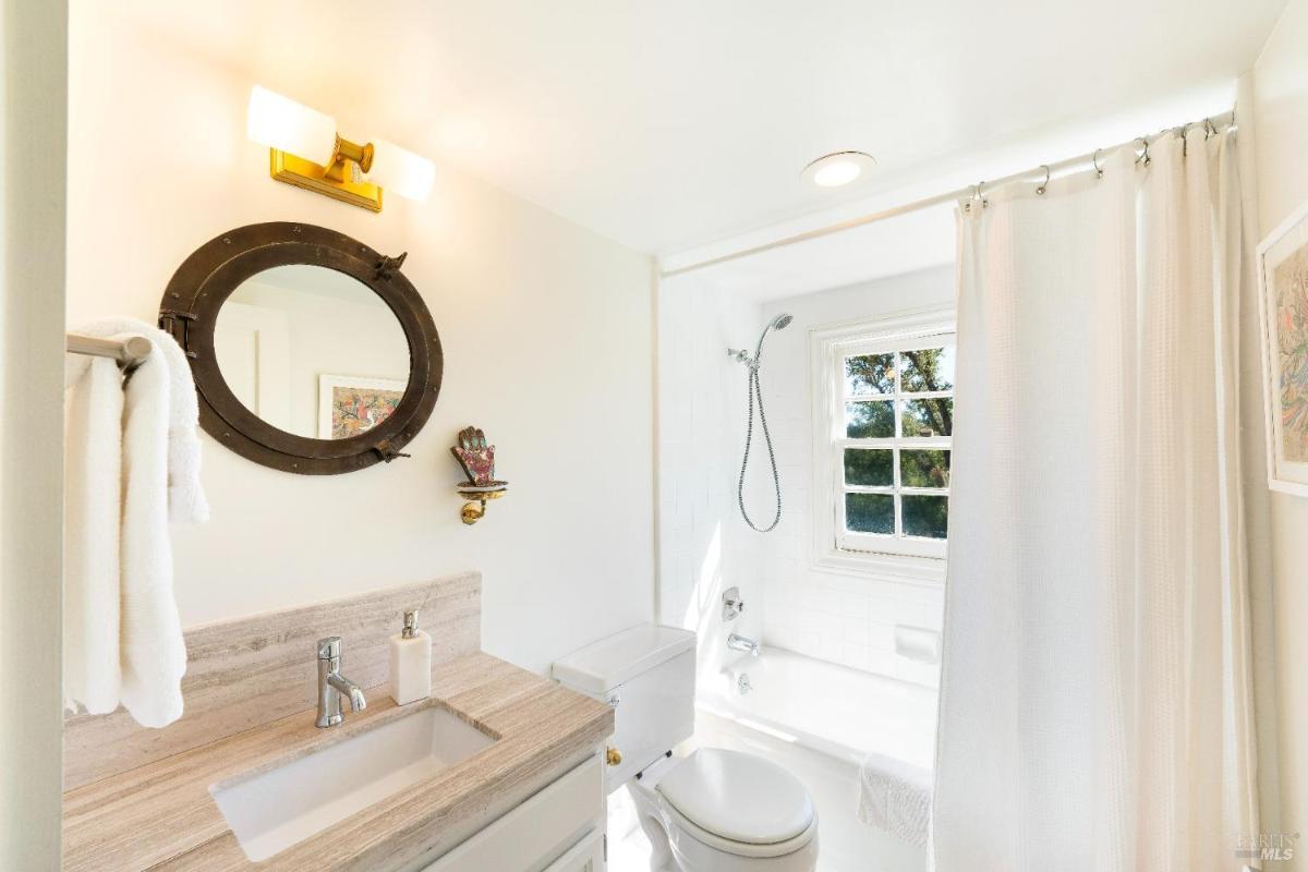 A bathroom featuring a sink, toilet, shower, and bathtub with a window.