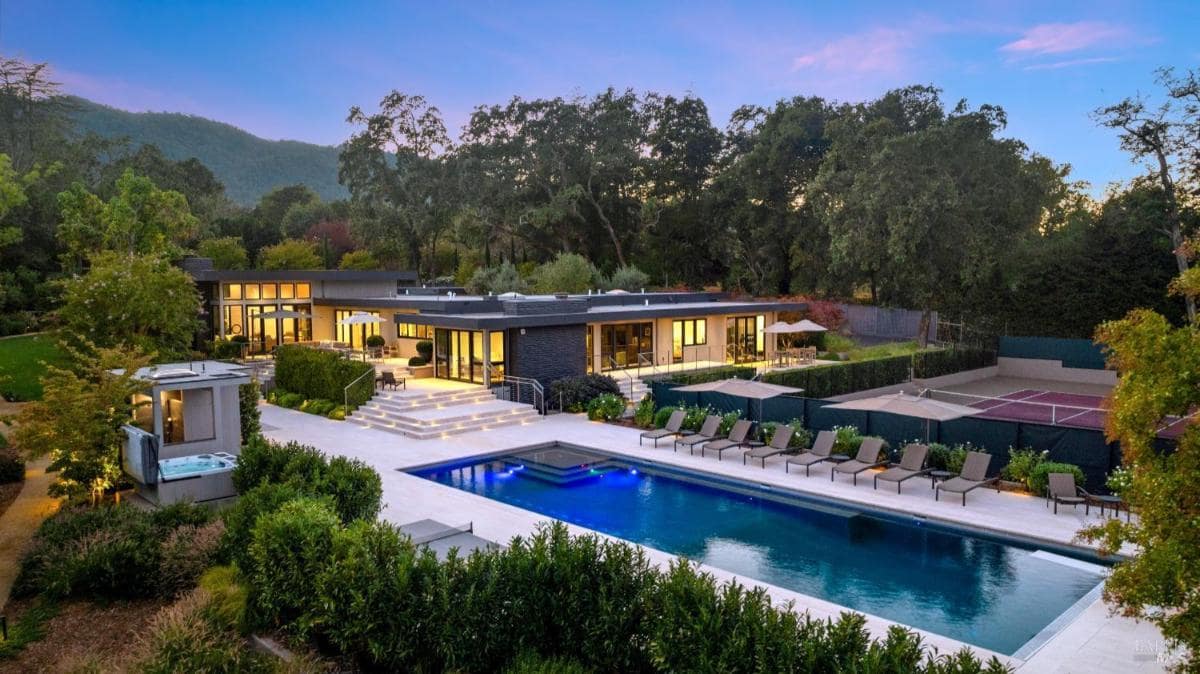 A modern backyard with a large swimming pool, surrounding lounge chairs, a staircase leading to a terrace, and a hot tub located to the left.