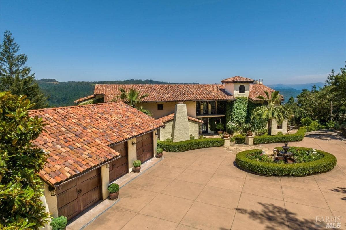 A large house with terracotta roofs and a driveway, set in a landscaped area.