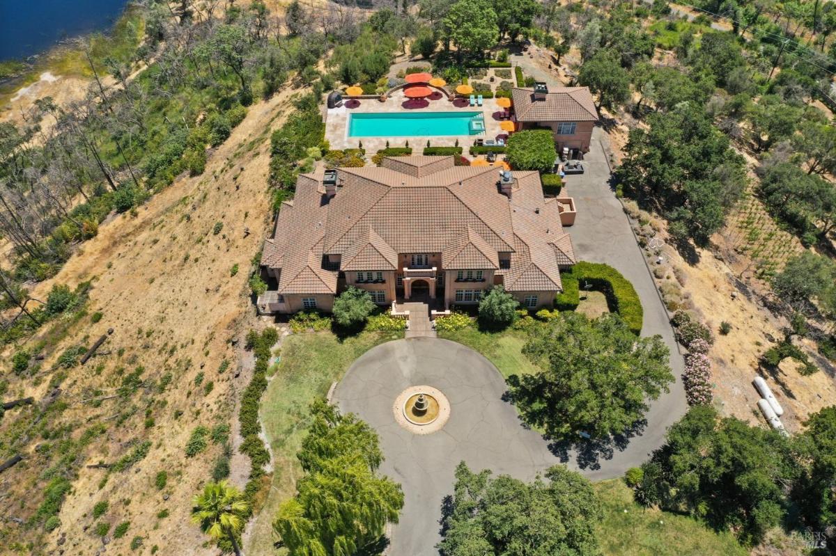 An aerial view highlights the mansion, circular driveway, outdoor pool, and surrounding landscape. 