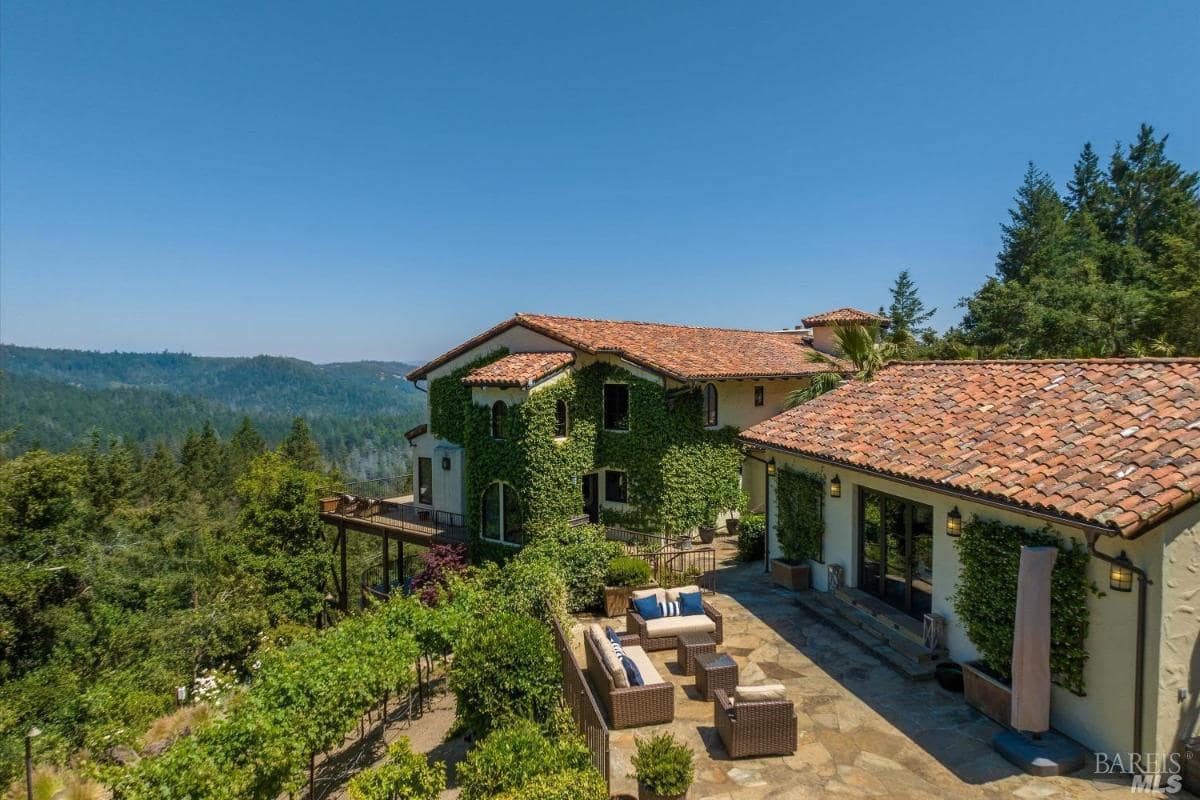 A house with ivy-covered walls, terracotta roofs, and an adjacent patio area.