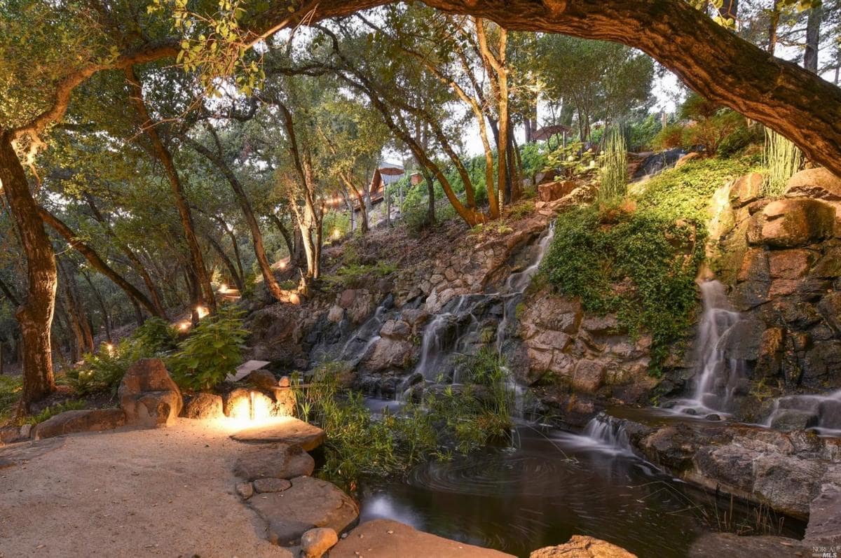 A stone waterfall feature surrounded by trees and pathways.