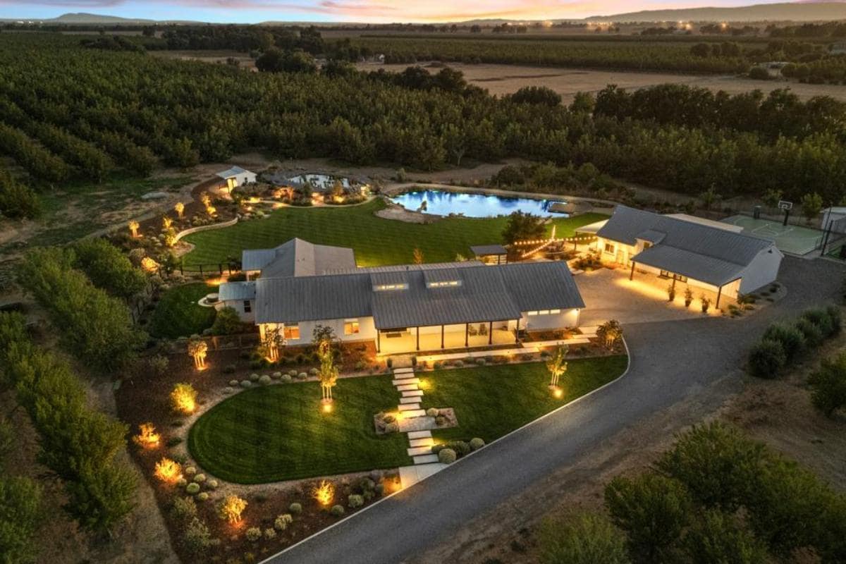 Aerial view of a large property with a house, pool, and orchard.